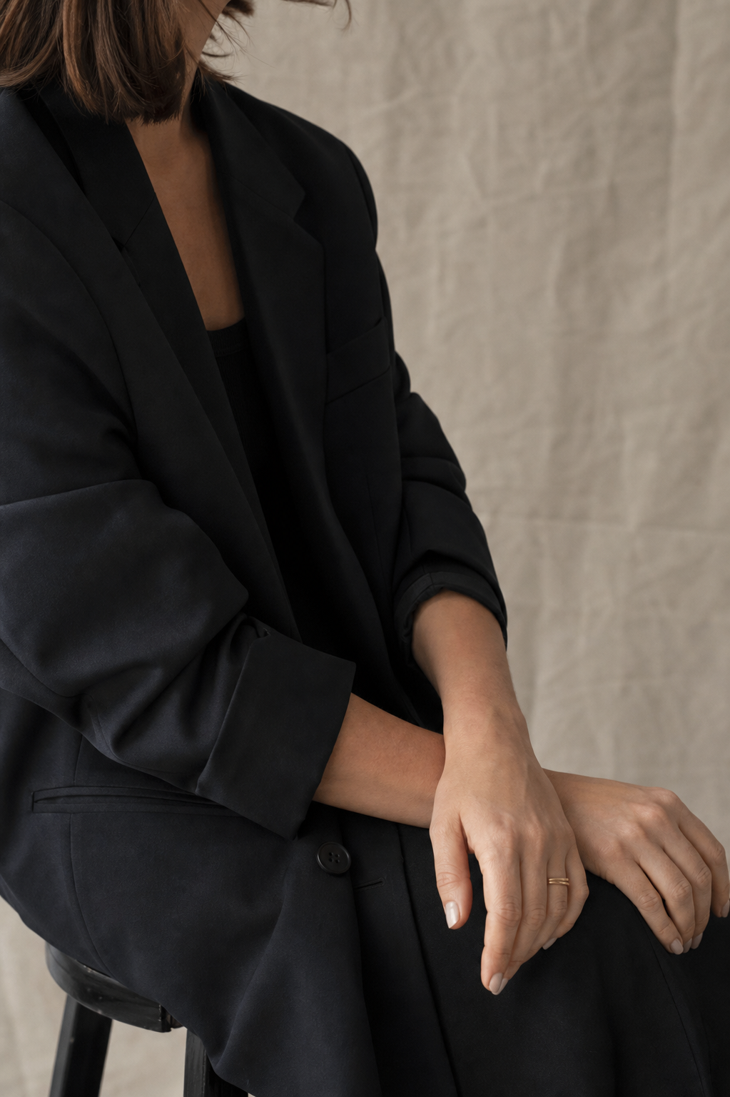 Ruhiges Portraitdetail mit dunklem Blazer vor neutralem Hintergrund